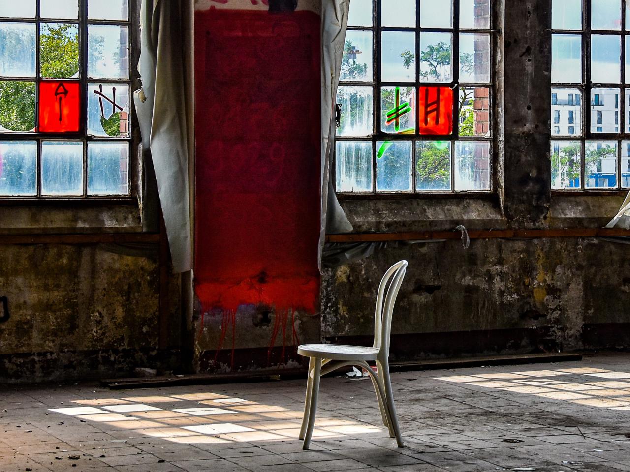 Lost Place - Ein Stuhl steht in einem verlassenen Raum eines Fabrikgebäudes. Im Hintergrund befinden sich kaputte Glasfenster. © Archäologisches Museum Hamburg