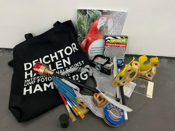 Materialkoffer Museum zum Anfassen für Menschen mit Lernschwierigkeiten in den Deichtorhallen Hamburg - © Museumsdienst Hamburg, Steffi Reimers Das Foto zeigt Objekte aus dem Materialkoffer, die man bei der Führung benutzt: Pinsel, eine Blechdose mit der Aufschrift Caviar, eine Krone und ein Zepter aus Plastik, Karten mit optischen Täuschungen, eine alte Fotokamera, eine Feder, Holzherzen, Spielgeld und Negative.