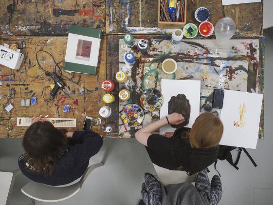 EXPRESS YOURSELF KUNSTWORKSHOP: Farbexperiment - ©Deichtorhallen, Foto: Henning Rogge Zwei Personen sitzen an einem Tisch und malen mit bunten Farben auf Papier. Die Kamera fotografiert sie von oben.