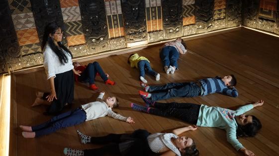 Fantasiereise, Gruppe liegend im Haus Rauru, MARKK - © Museumsdienst Hamburg, Muriel Borchert Foto einer Gruppe Kinder, die im Haus RAURU liegen.