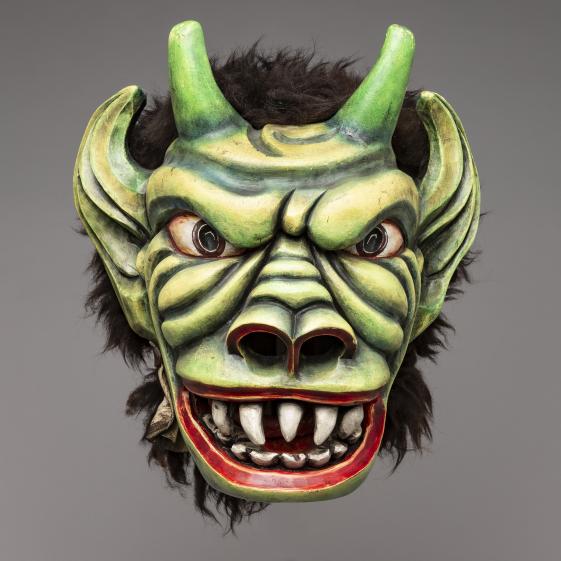 „Klaubaufmaske“,Lienz (Tirol), 1977,Slg. Otto König - © MARKK, Foto: Paul Schimweg Die Fotografie zeigt eine grüne Maske mit Hörnern, aufgerissenen Mund und stark betonter Mimik. Die Lippen und Nasenlöcher der Maske sind rot kontrastiert.