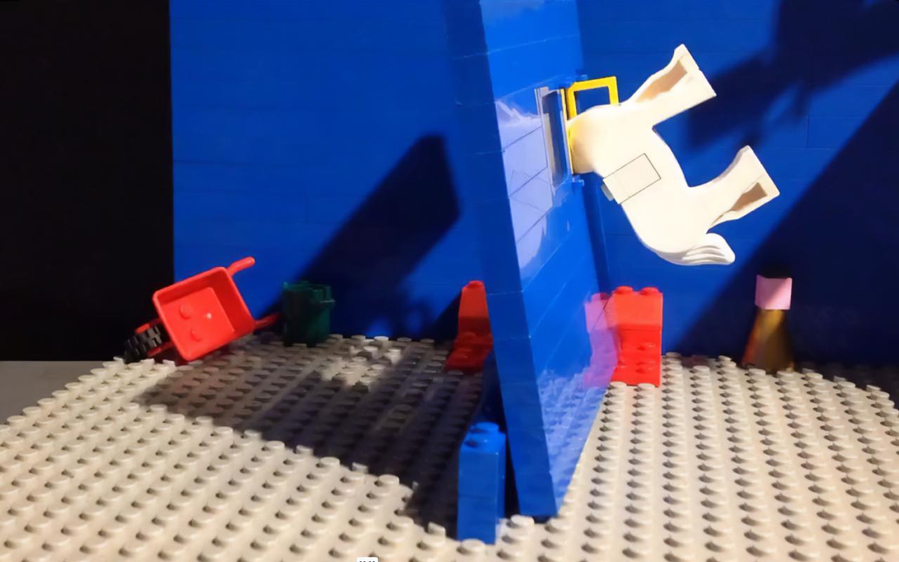 Einzelbild aus einem Lego Trickfilm: eine Kulisse aus blauen Lego Steinen, im Hintergrund eine Lego Schubkarre. Im Bildzentrum eine umstürzende Wand, in der ein Lego Pferd